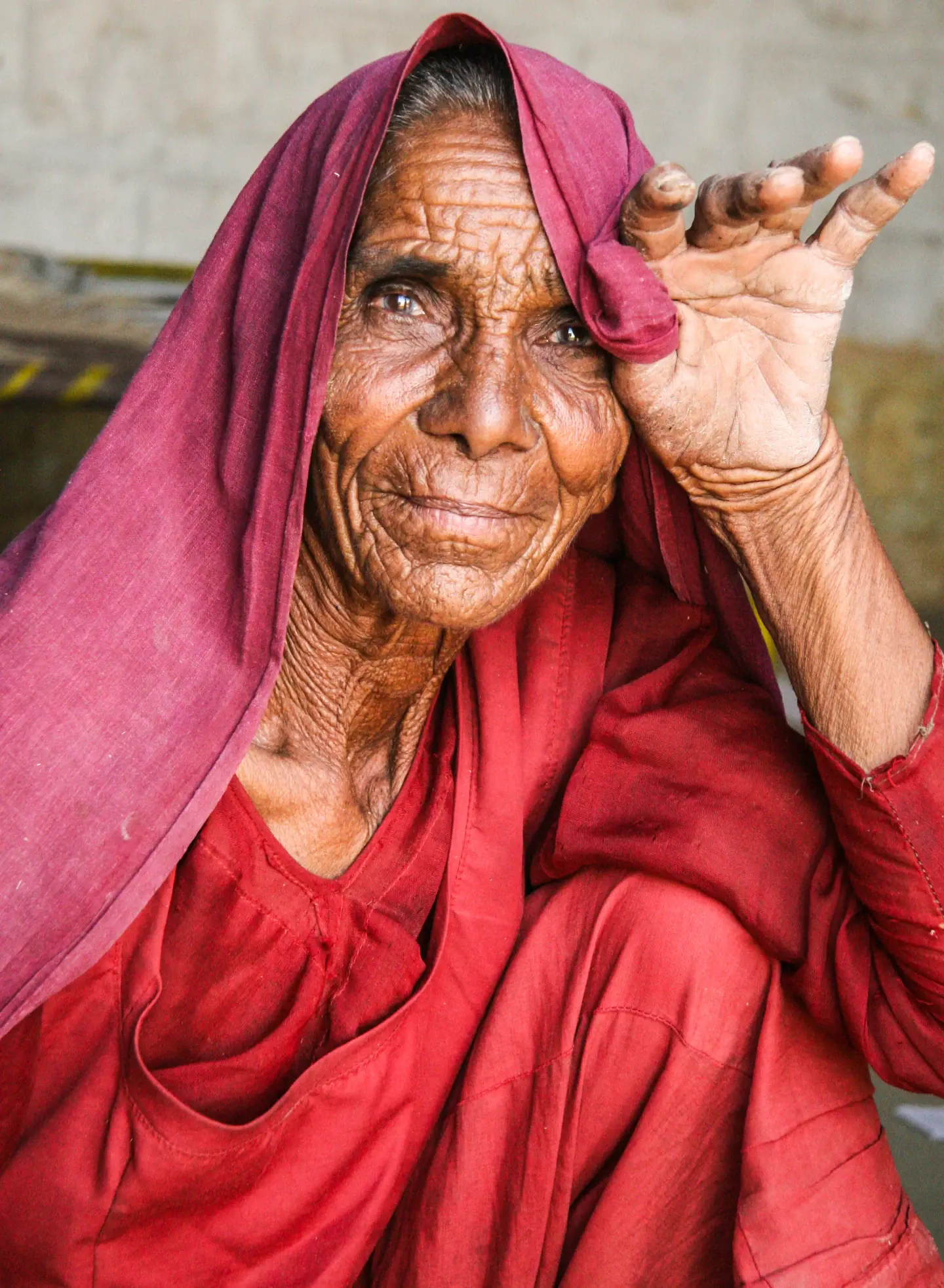 Mulher idosa com véu vermelho sentada em rua de Jaisalmer