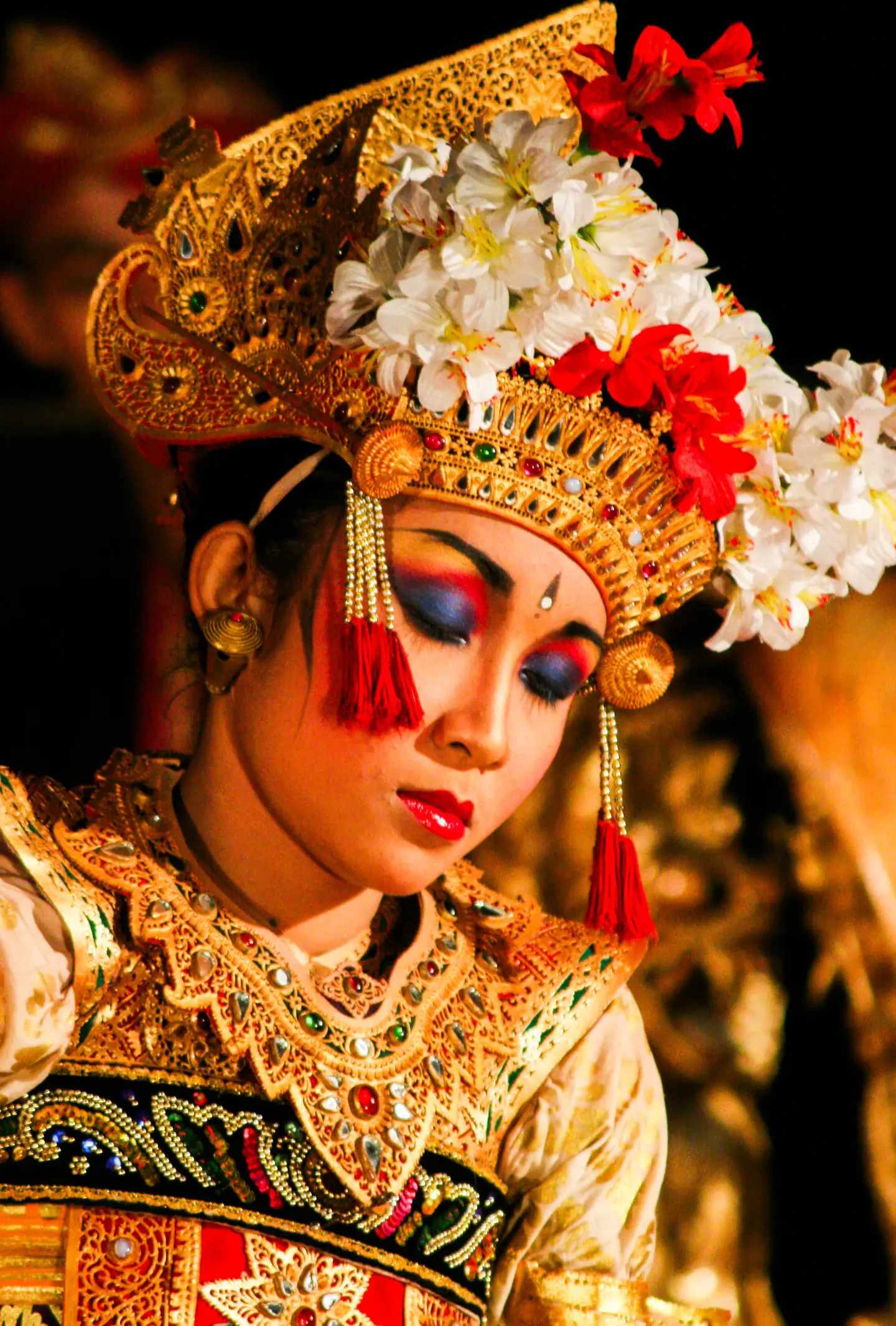 Dançarina em Ubud com coroa florida e traje bordado em cena noturna